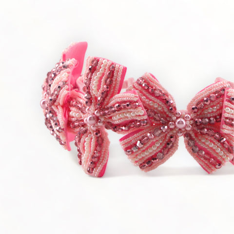 Best in luxury hair acessories for children by Sienna Like to Party.  This childs pink bow headband is entirely hand stitched with hundreds of metalic pink crystals and pearls.