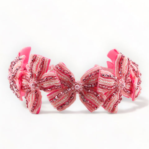 the ultimate in luxury for children.  This hand-beaded girls bow headband is created entirely by hand.  Stitching hundreds of individual metalic pink crystals and pearl to quality petersham bows.  The perfect kids party or. special occasion hair accessory.