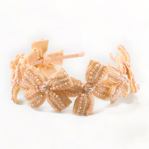 The ultimate in childrens luxury hand beaded hair accessories.  This childs bow hair band is intricately hand stitched with pastel apricot cut crystals and pearls for ultimate sparkle.